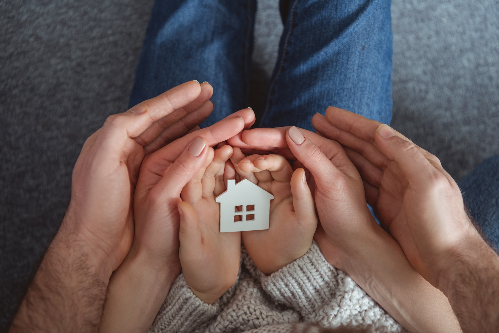 cropped shot of family holding small house model in hands
