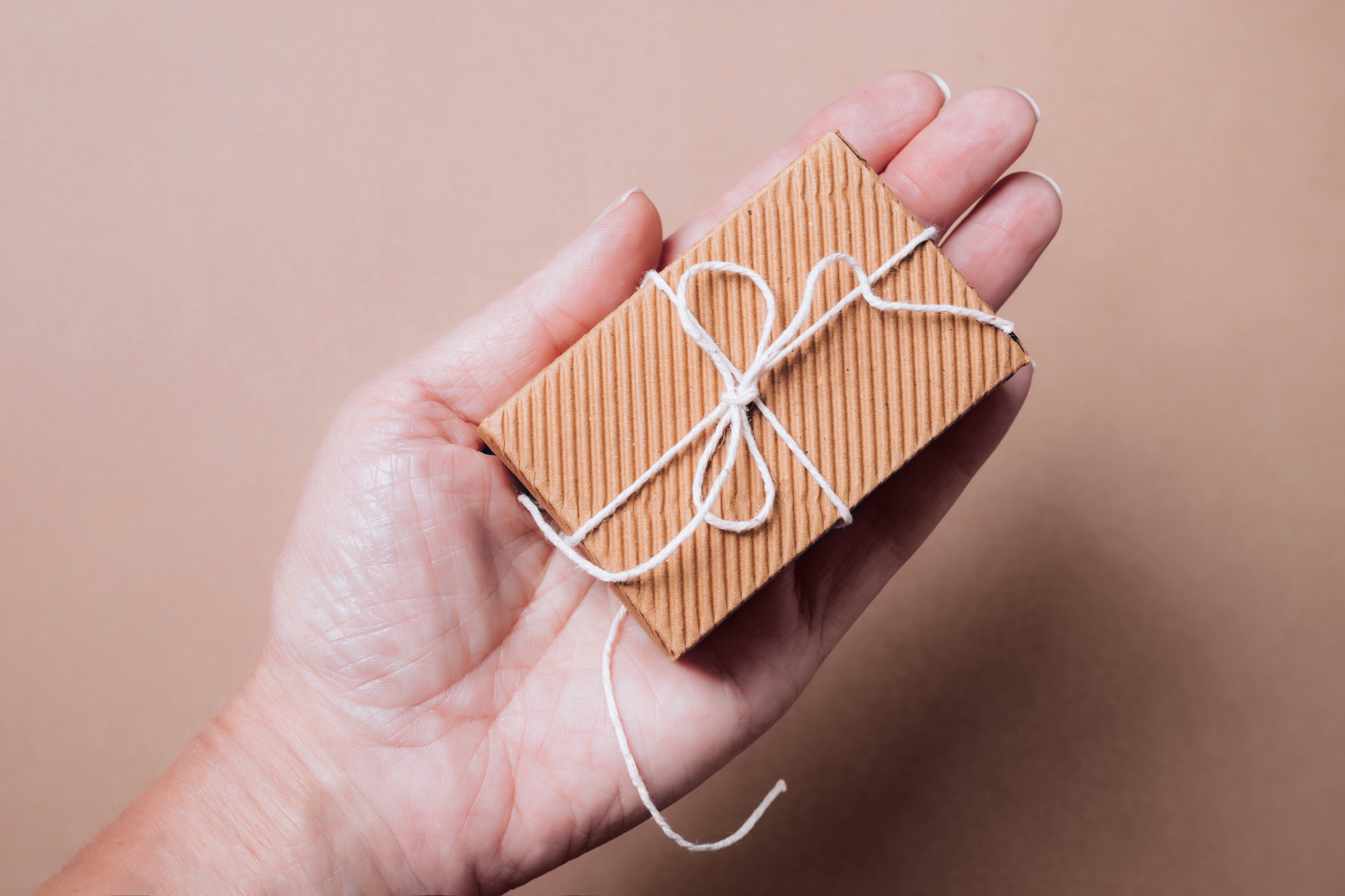 Cute small corrugated gift box with natural string in female hand