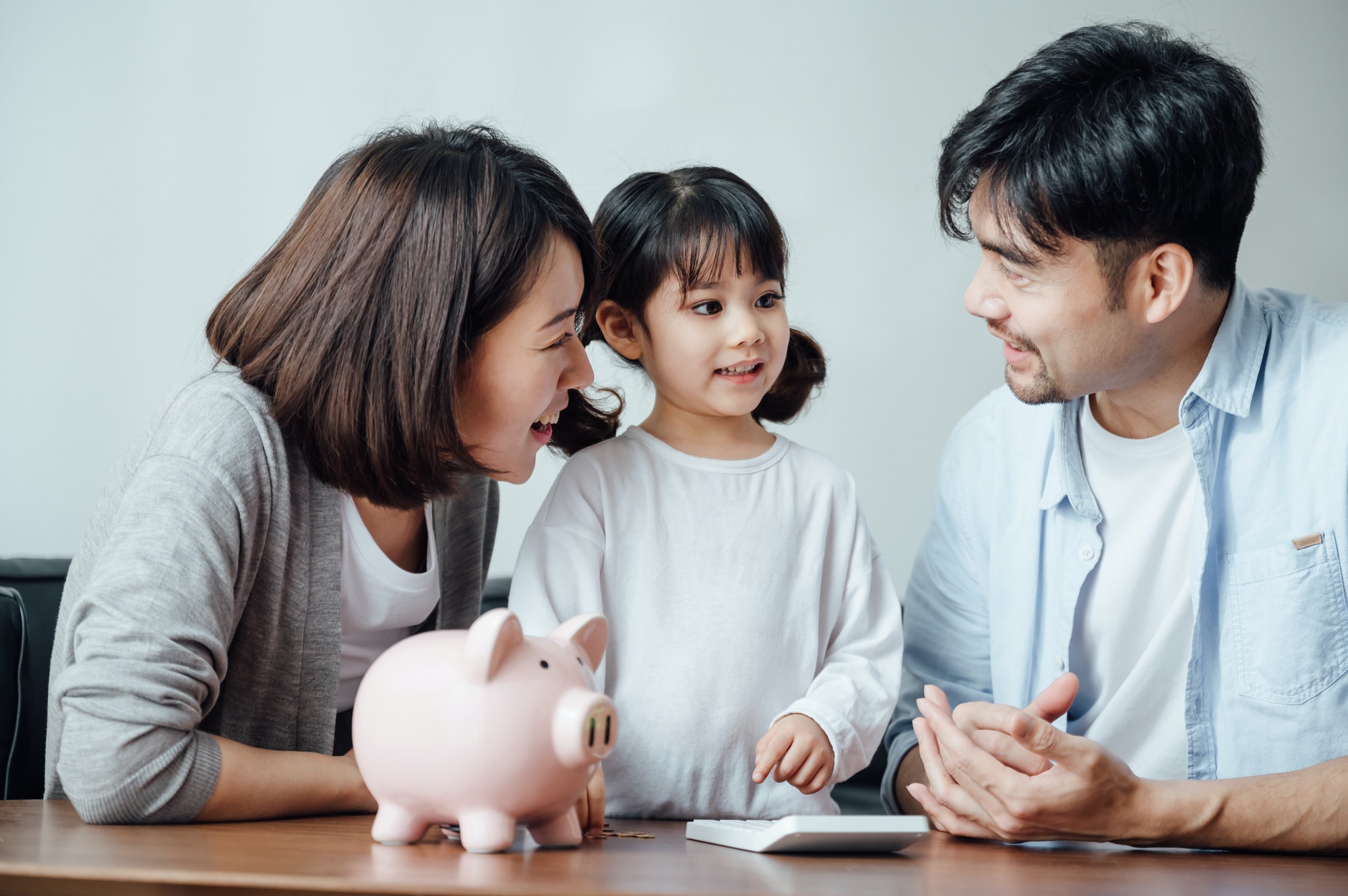 Parents teaching daughter to save money at home