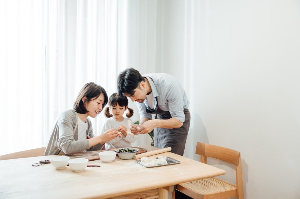 Parents teaching daughter to make dumplings at home